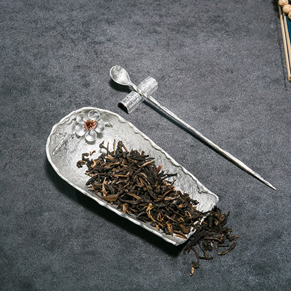 Close-up of the tea spoon, ideal for loose leaf tea, next to the tin tea holder.