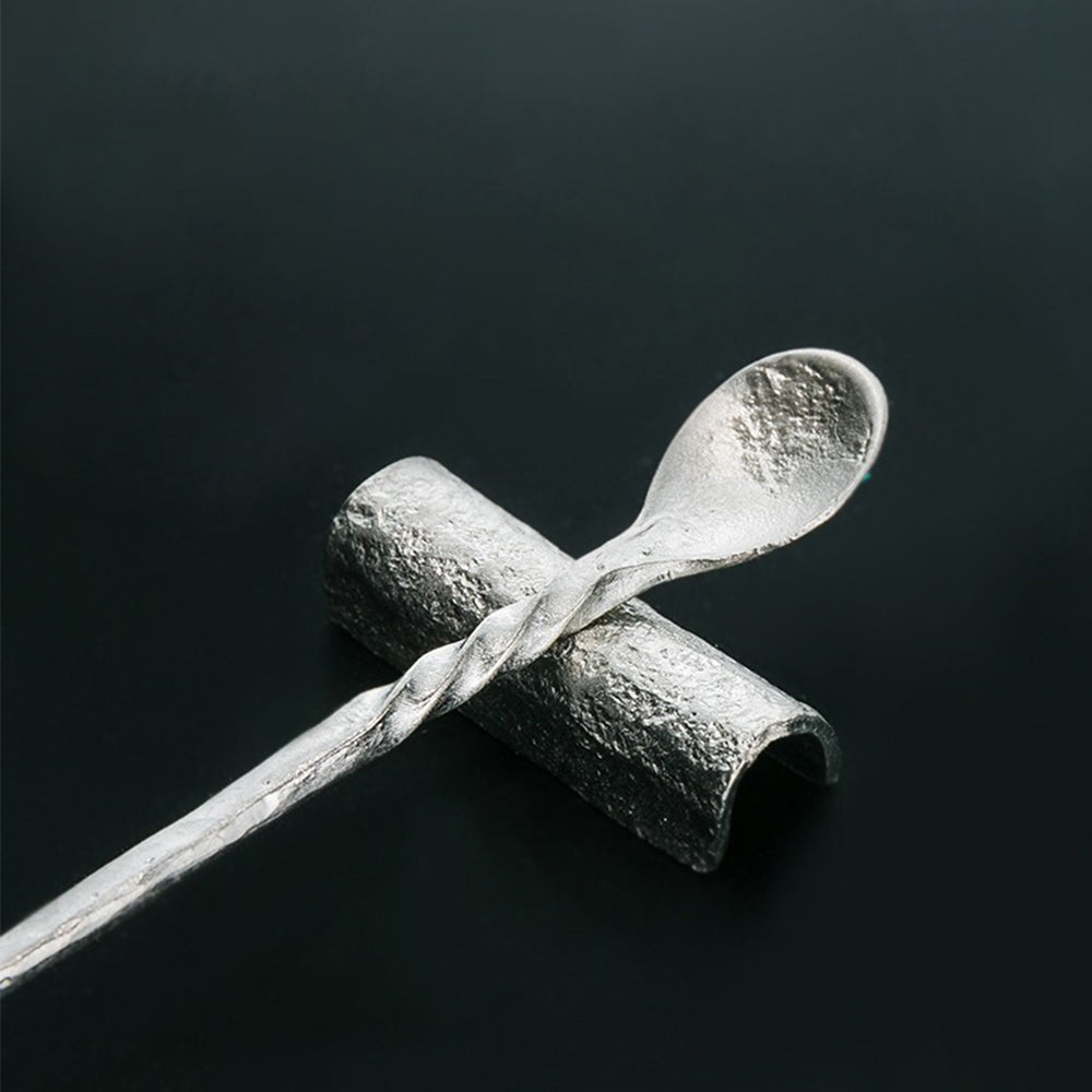 Close-up of the tea spoon, ideal for loose leaf tea, next to the tin tea holder.
