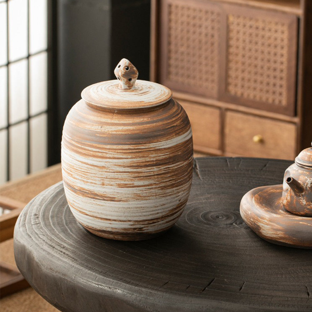 Elegant ceramic storage jar on a wooden table, filled with loose leaf tea, showcasing its functionality.