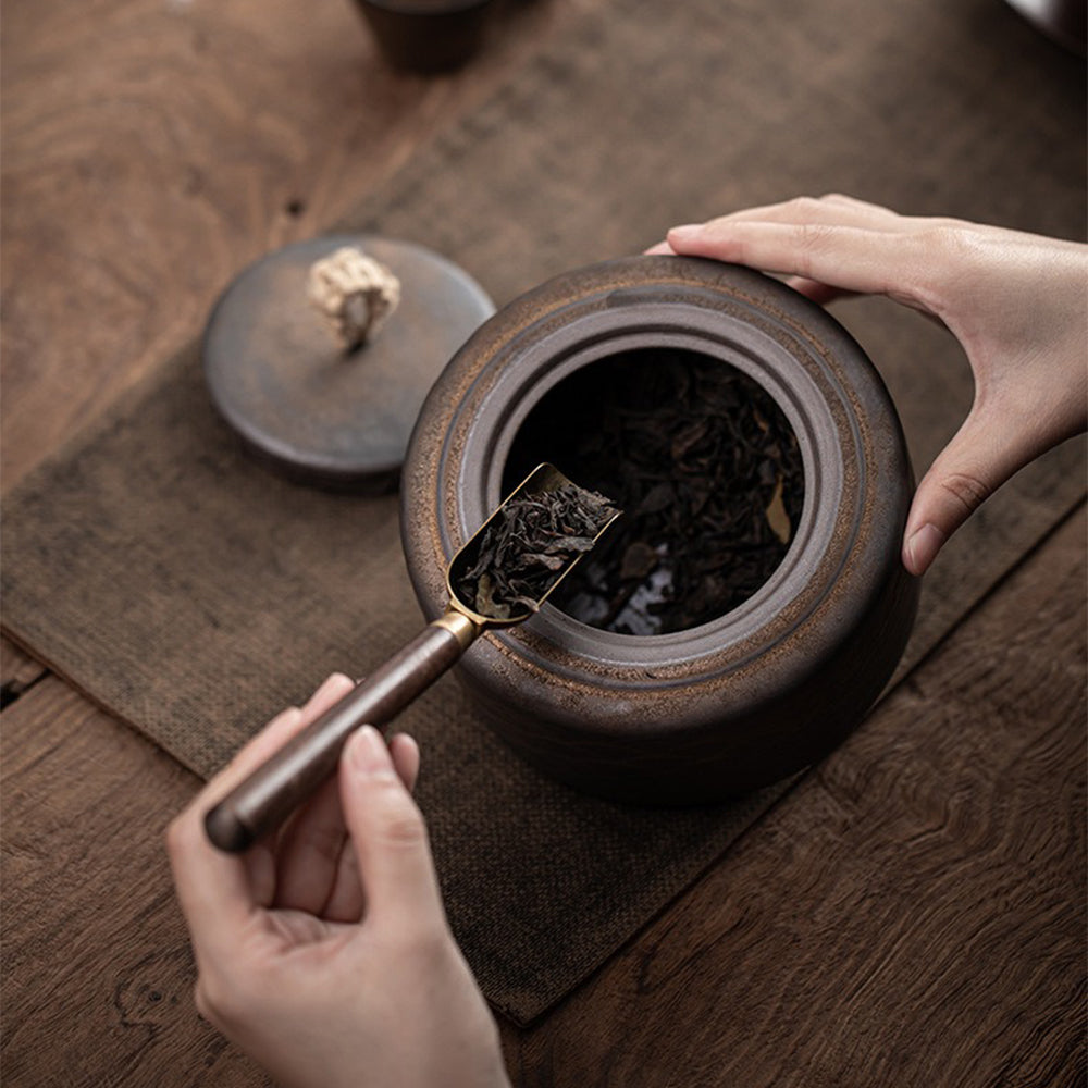 Tea caddy on a kitchen counter with loose tea leaves nearby, showcasing vintage design