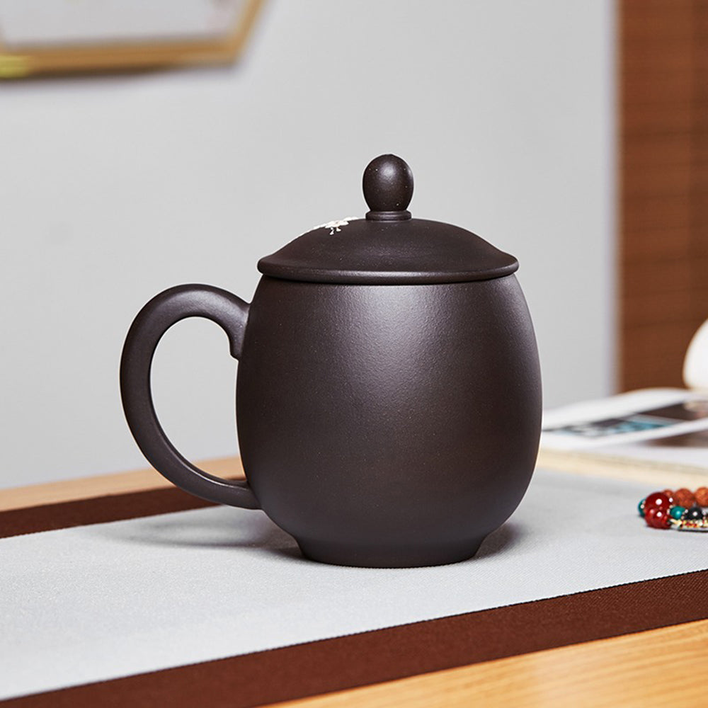 The handcrafted purple clay teacup filled with steaming tea on a table.
