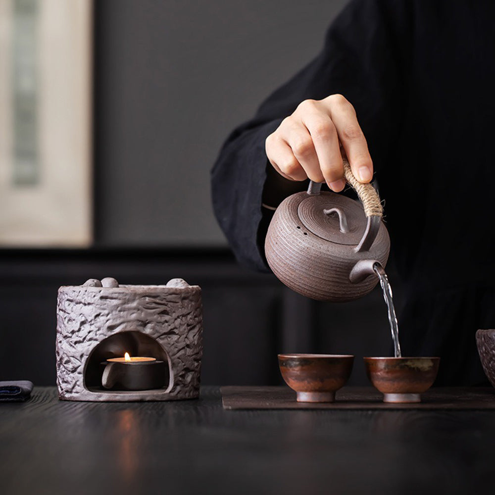 Teapot with candle warmer set on a wooden table, creating warm ambiance