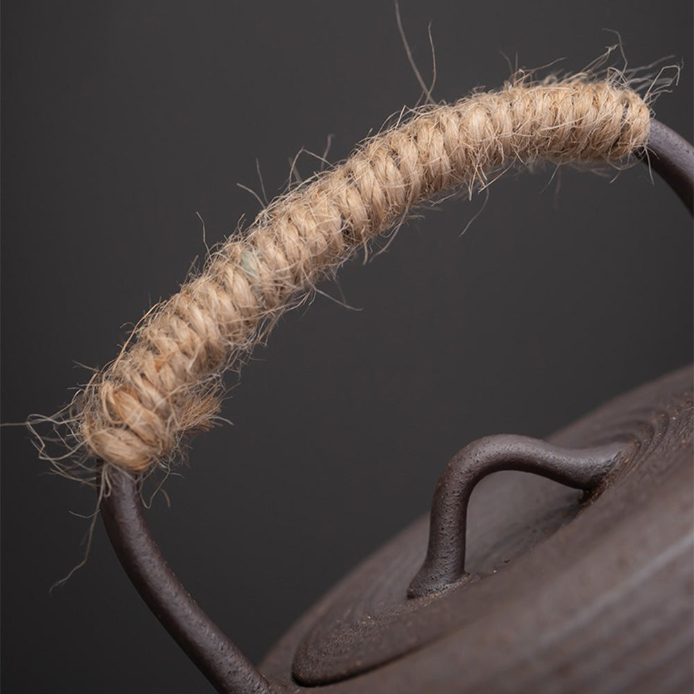 Close-up of textured handmade pottery teapot with frosted glaze and hemp handle