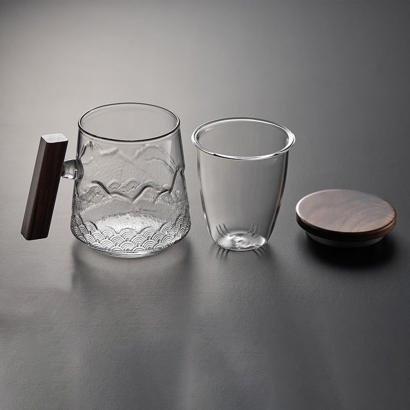 User  enjoying herbal tea from a stylish glass mug with wooden lid