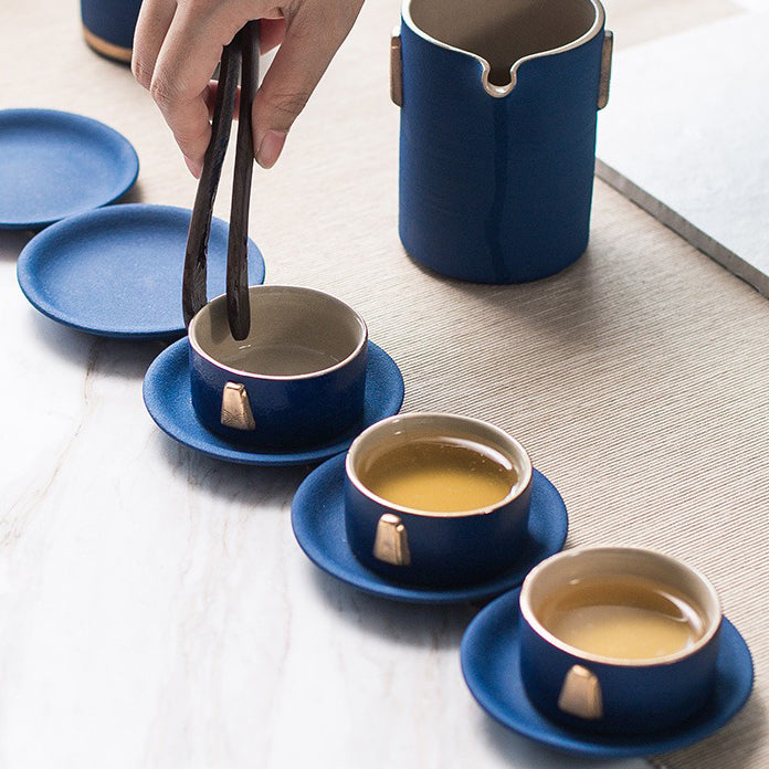 Elegant blue tea set with golden handles on a wooden table, showcasing its artistic design.