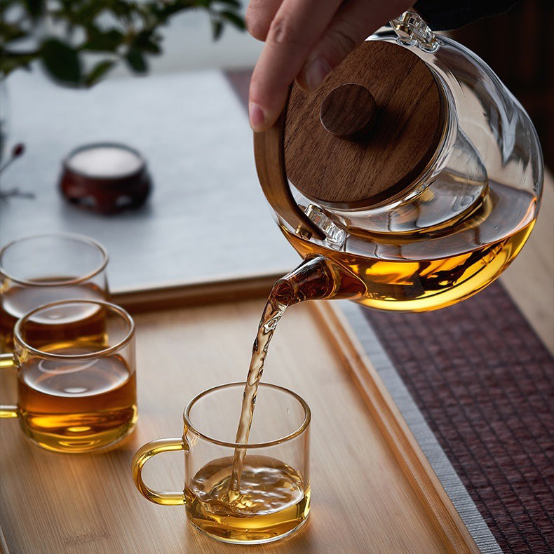 Elegant heat resistant glass teapot with infuser showcasing blooming tea leaves.