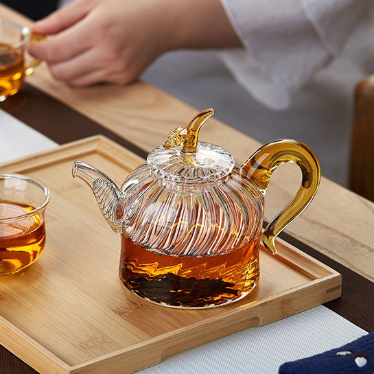 Teapot displaying blooming tea leaves inside the transparent glass, highlighting the beauty of the brewing process.