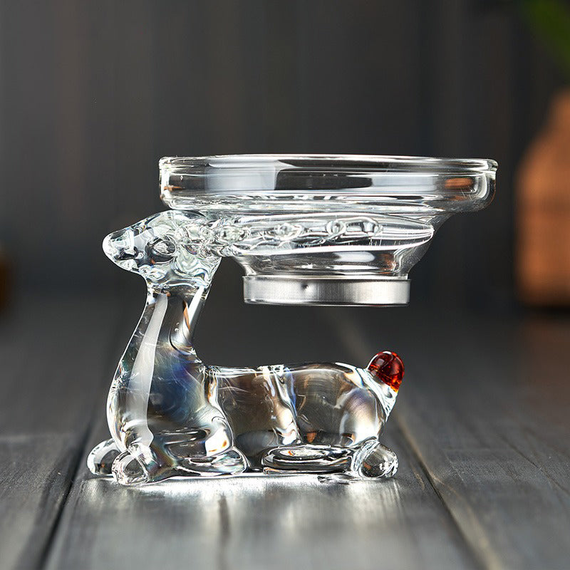 Glass strainer in use, filtering loose leaf tea into a fair cup, highlighting its functionality.