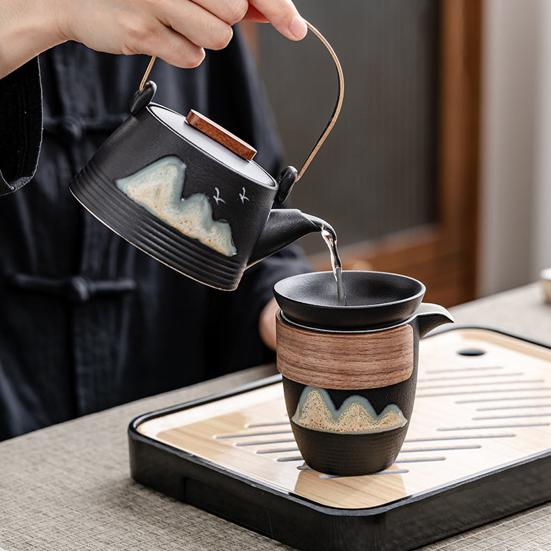 Black pottery travel tea set with mountain design, ideal for on-the-go tea brewing