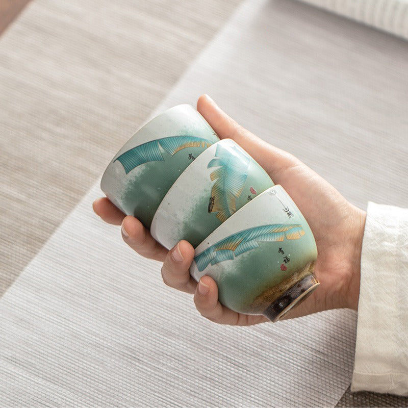 Close-up of traditional Chinese ceramic tea cups with banana leaf design, showing intricate craftsmanship
