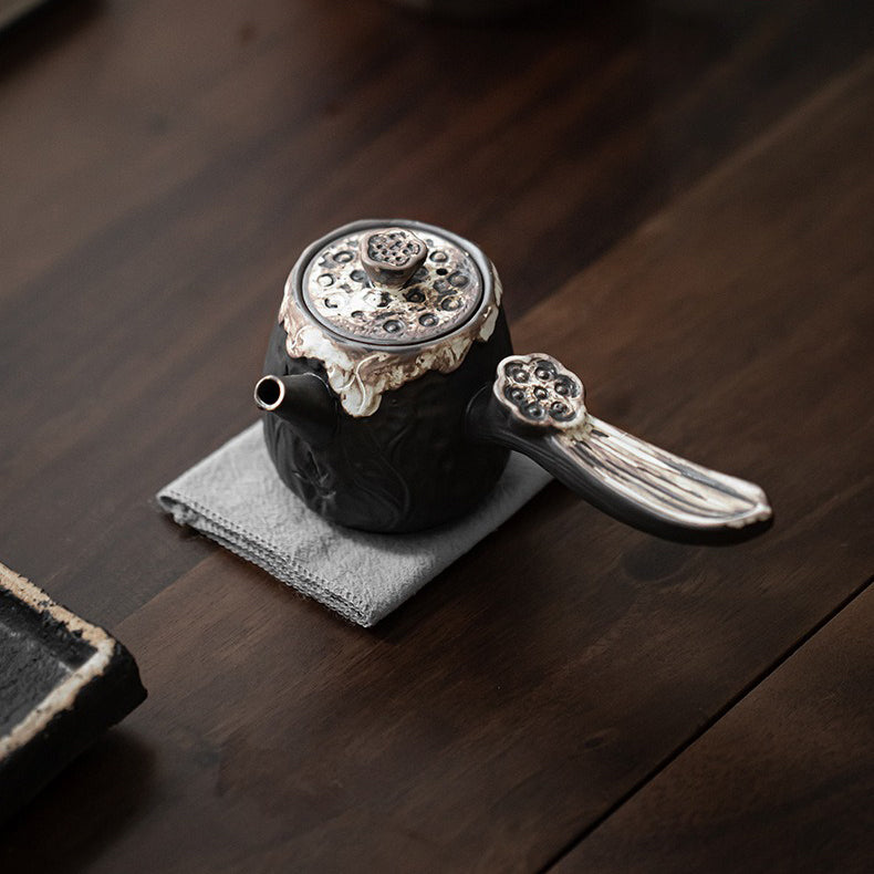 Ceramic lotus teapot on a tea table, artfully styled with tea leaves and cups.