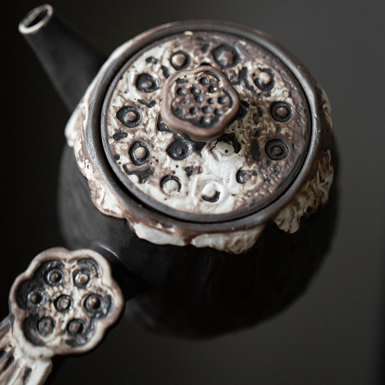 Ceramic lotus teapot on a tea table, artfully styled with tea leaves and cups.