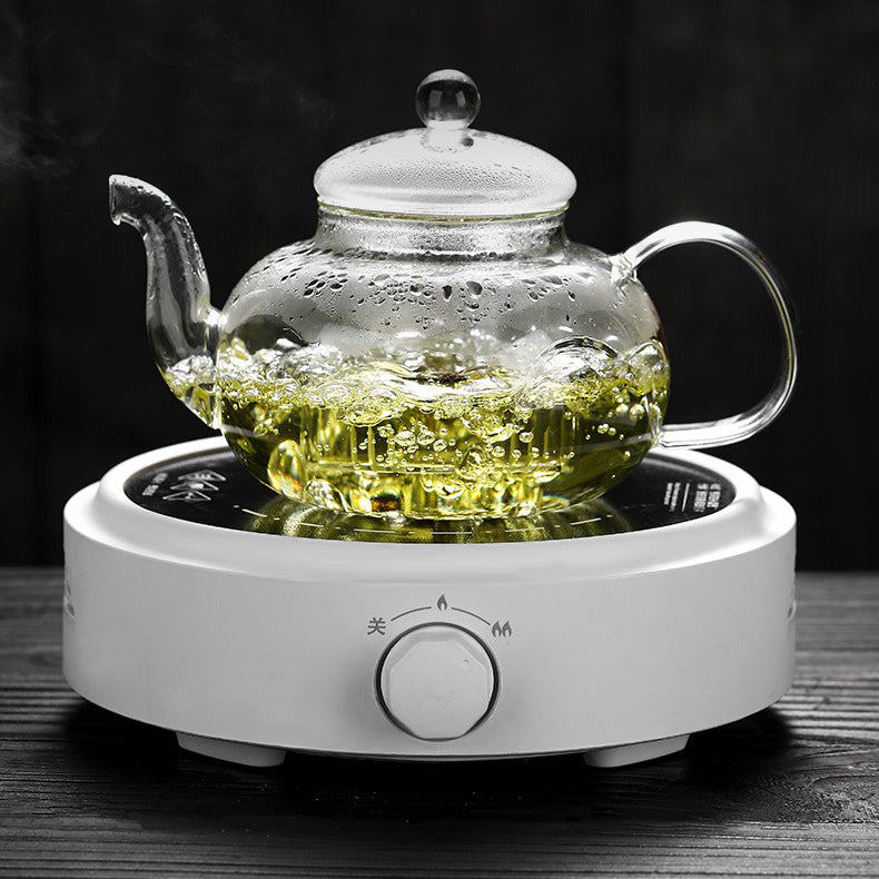 Hand holding a clear glass teapot with blooming tea inside, perfect for tea enthusiasts