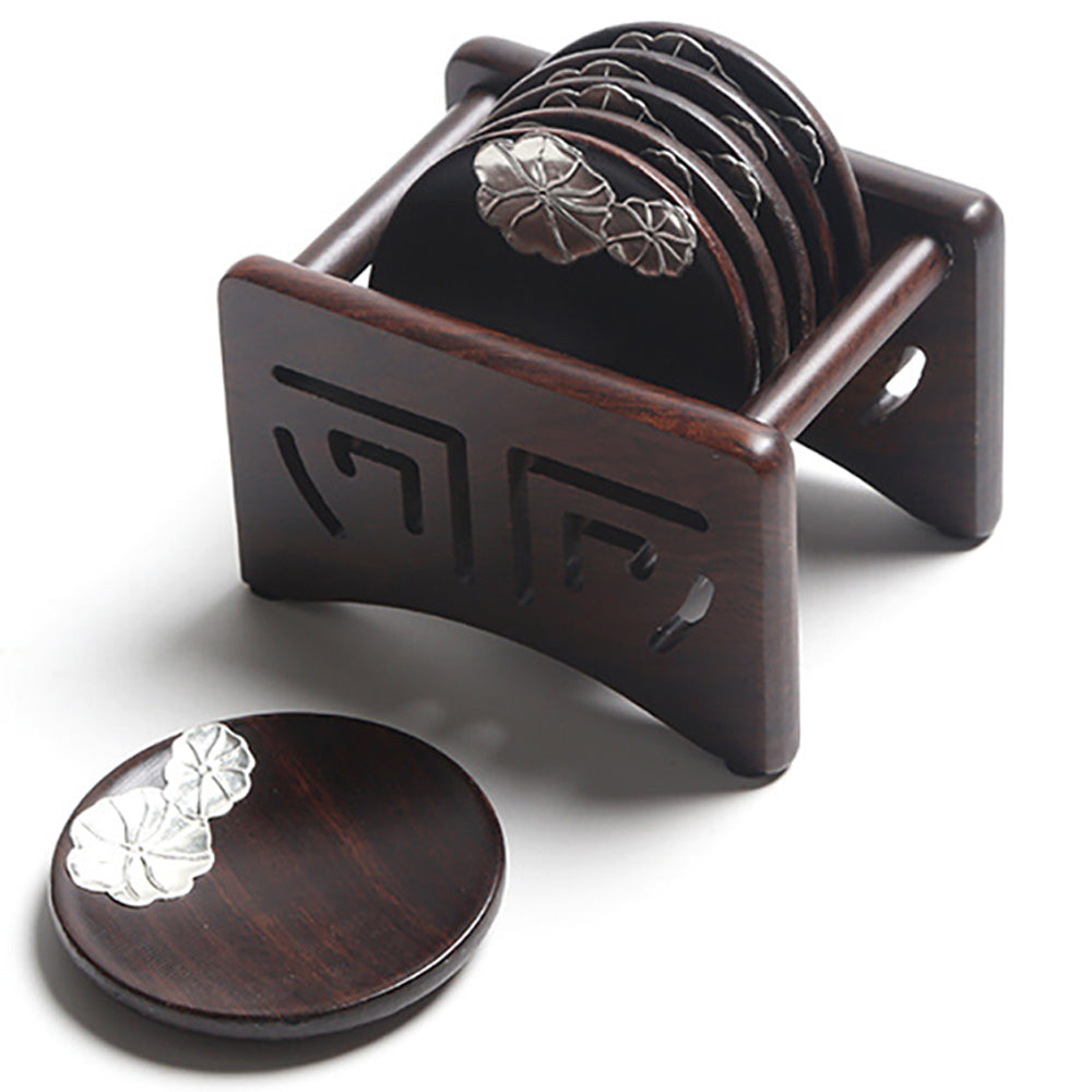 Top-down view of ebony coasters with silver lotus design arranged in holder on a wooden table