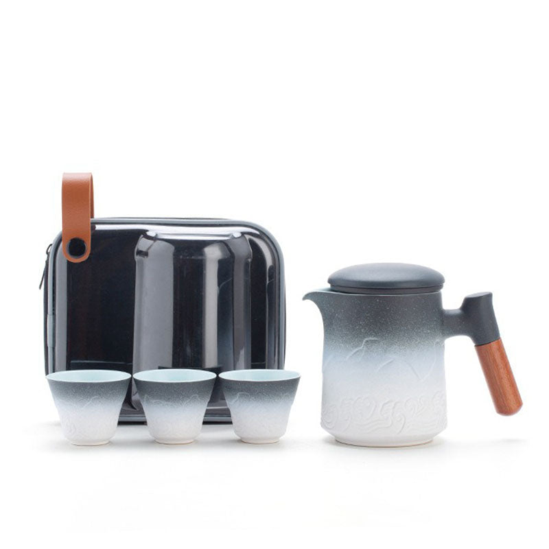 Close-up of ceramic teapot with wooden handle and scenic glaze finish—perfect travel tea set.