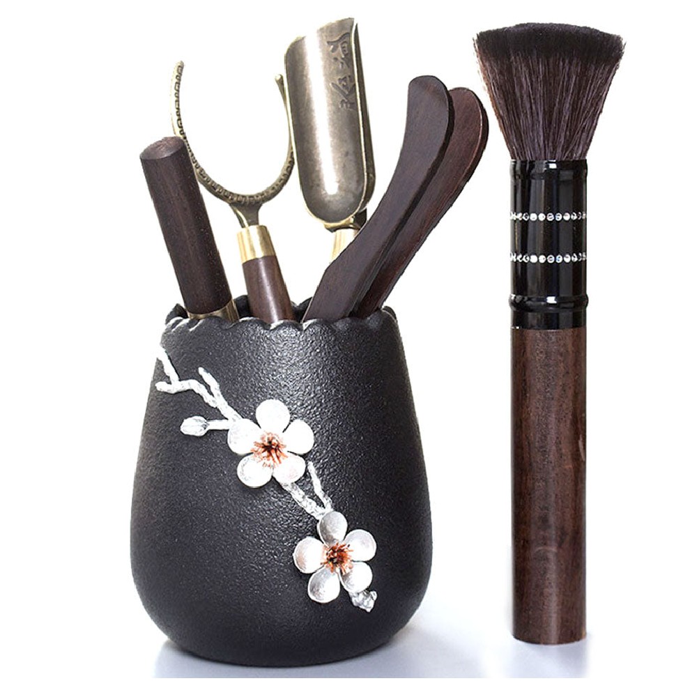 Ebony tea set with ceramic plum blossom holder and tea utensils arranged for a gongfu tea ceremony