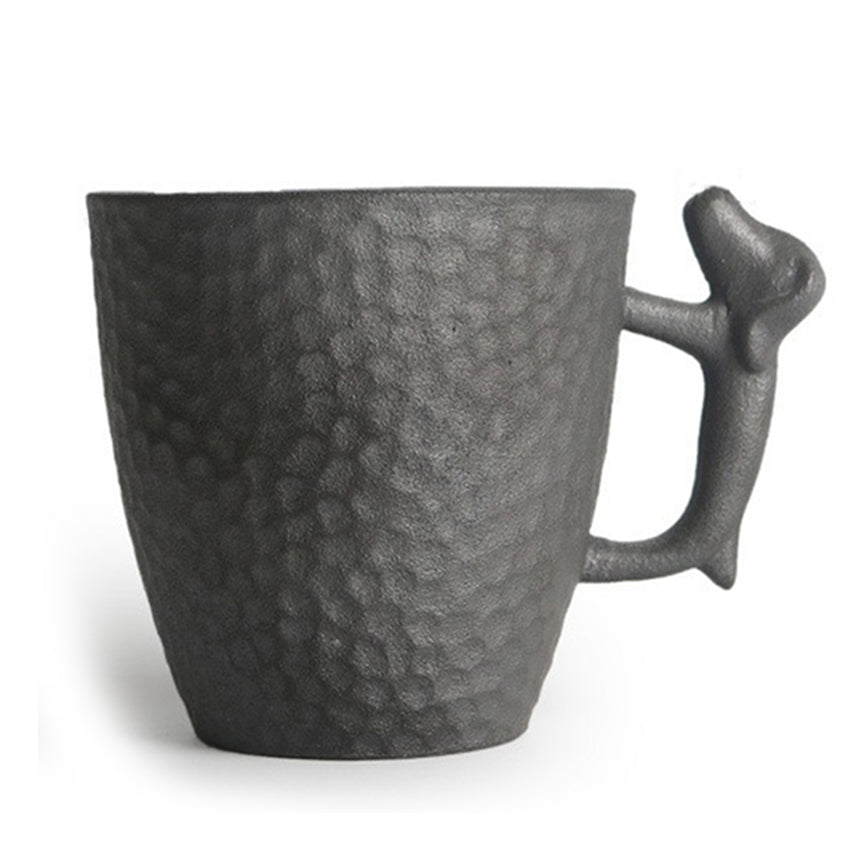 Front view of handmade Japanese tea cup with dog handle on a wooden table