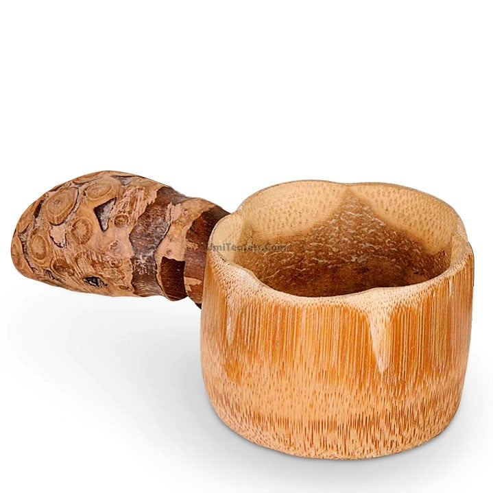 Bamboo tea strainer with handle placed over a cup, filtering loose leaf tea.
