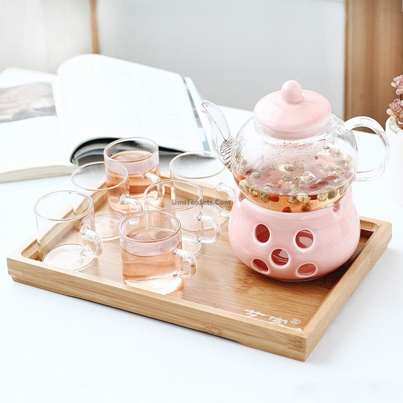 Glass tea set with pink porcelain warmer and teapot, perfect for herbal tea brewing